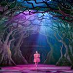 Mei (Victoria Chen) wearing a pink dress and walking through the forest.